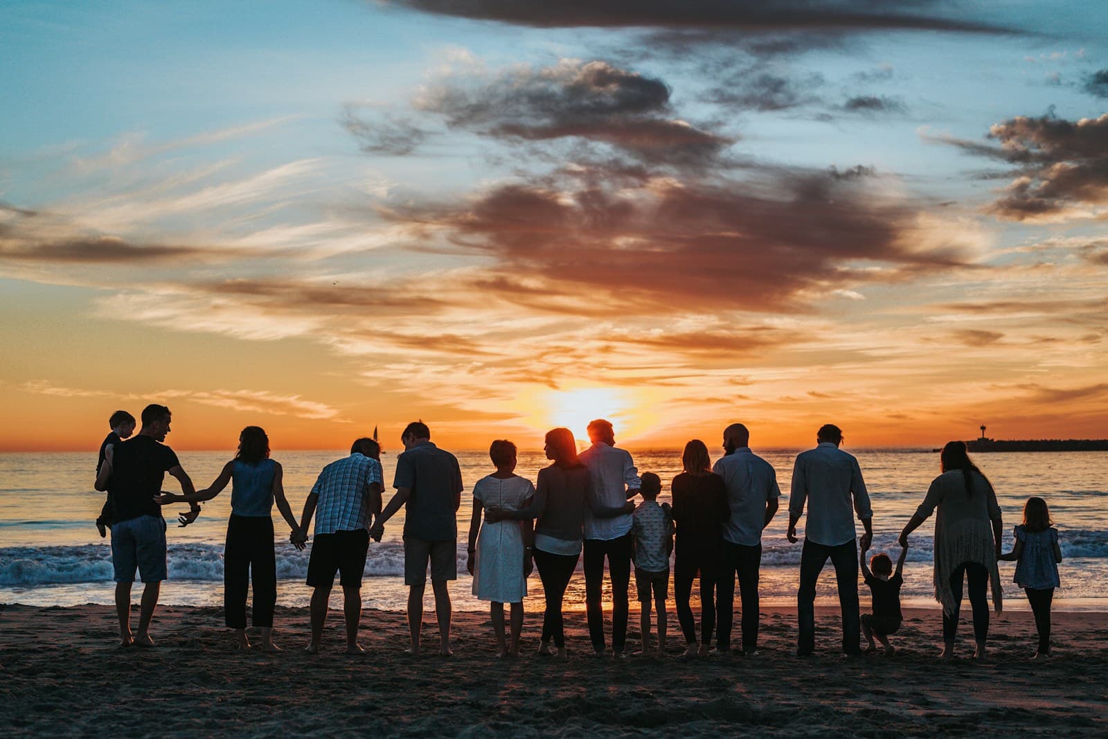 Famille sur la plage au soleil couchant, silhouettes rassemblées